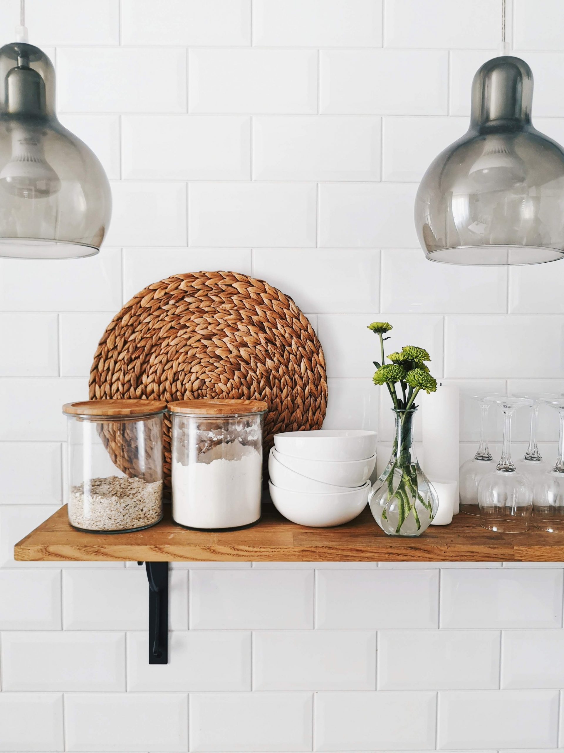 wooden open shelf with glass canisters and bowls and glasses on subway tile wall. Similar to Ramona Aline Home's farmhouse kitchen